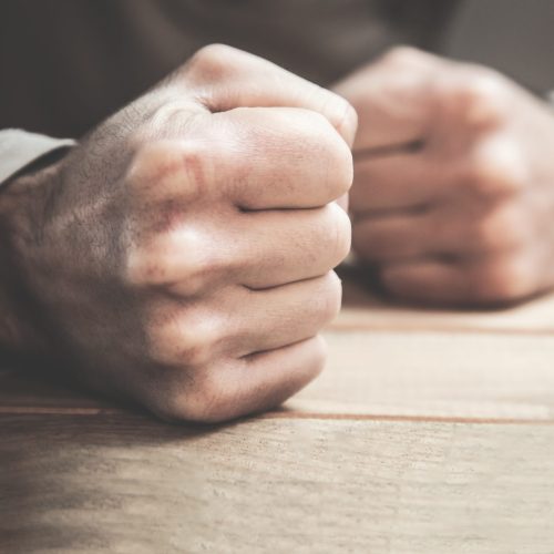 Angry man fists in the table.